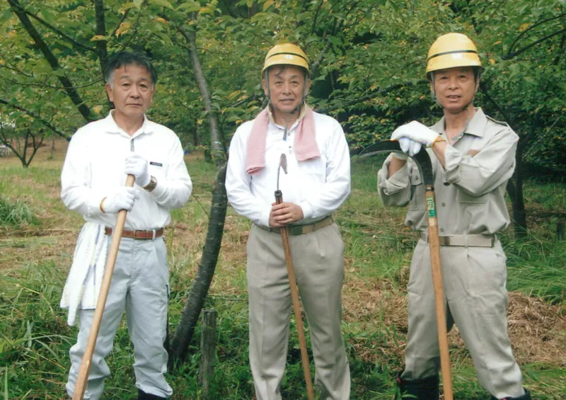 作業着とヘルメット姿で、森の整備に参加する